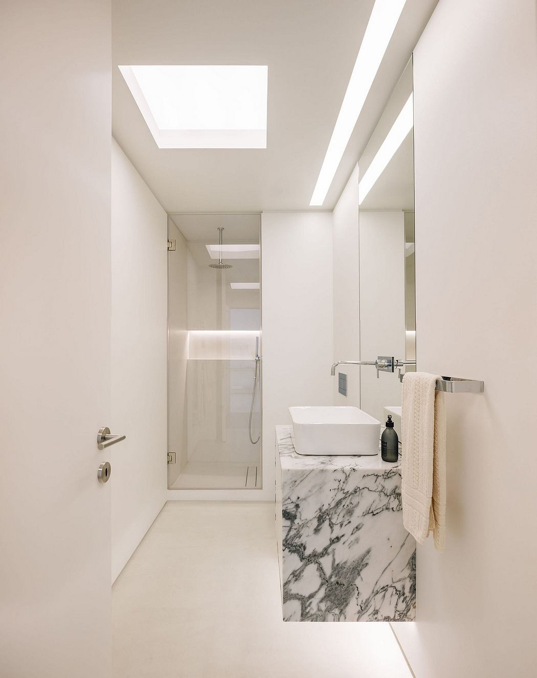 Sleek, modern bathroom with a marble vanity, glass shower, and an overhead skylight.