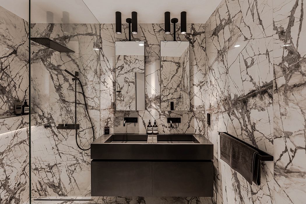 Modern bathroom with marble walls, double vanity, and black fixtures.