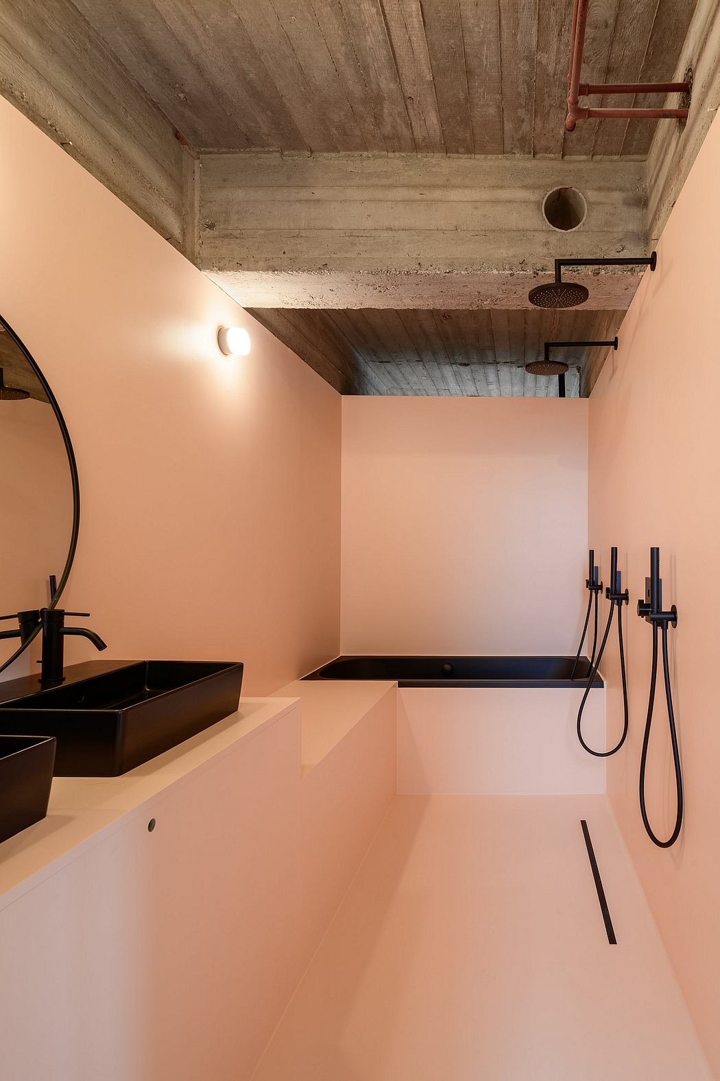 Minimalist pink bathroom with exposed concrete ceiling and sleek fixtures.
