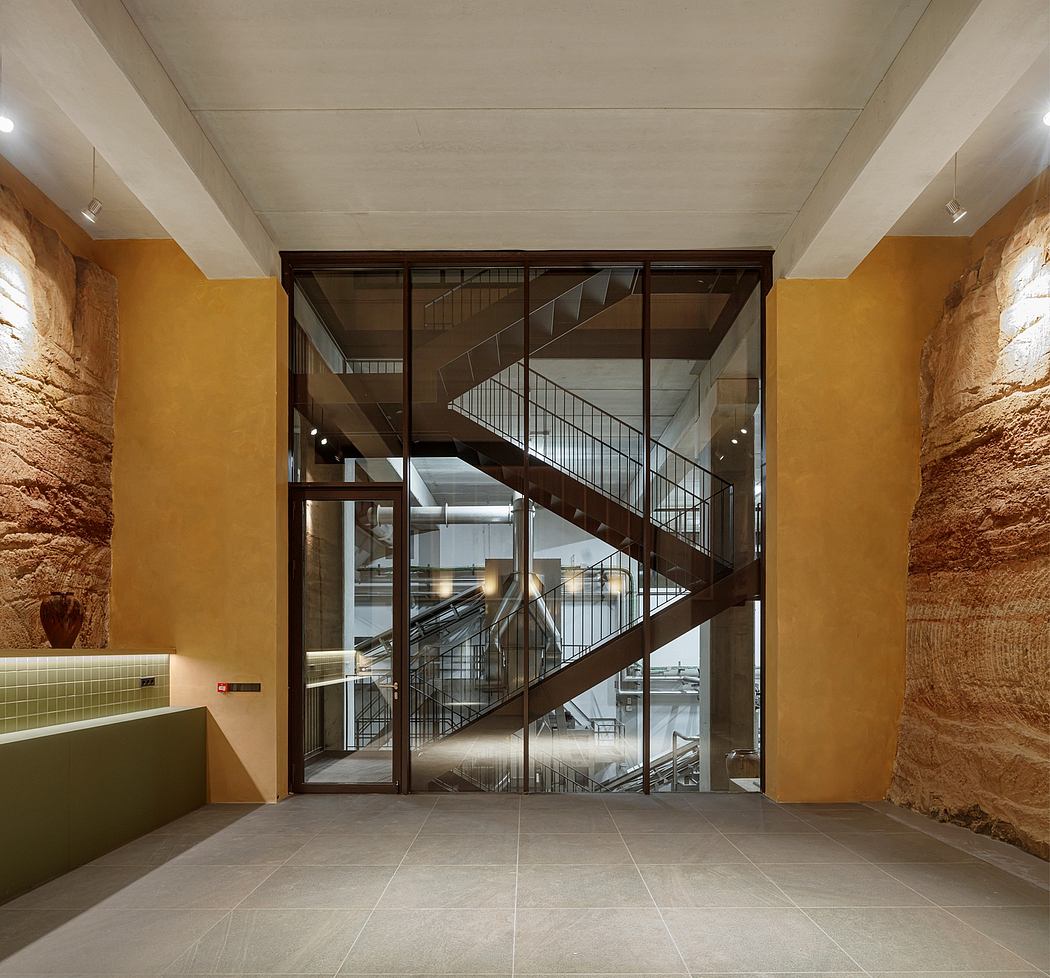 Modern glass staircase between rustic stone walls within an interior space.