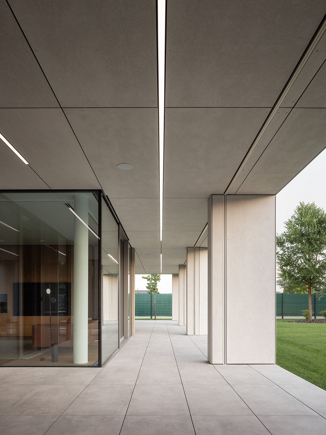 Minimalist corridor with sleek columns and glass facade.