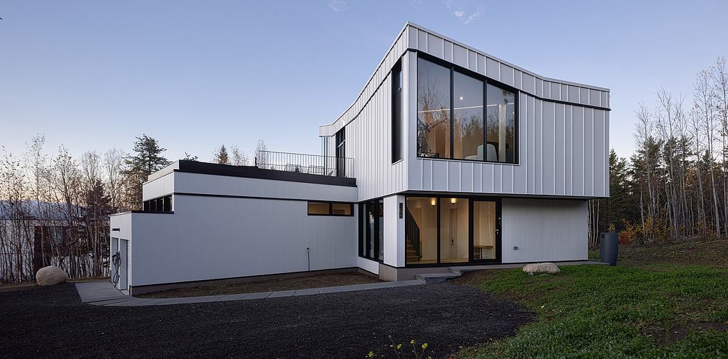 Modern two-story house with large windows and white exterior at dusk.