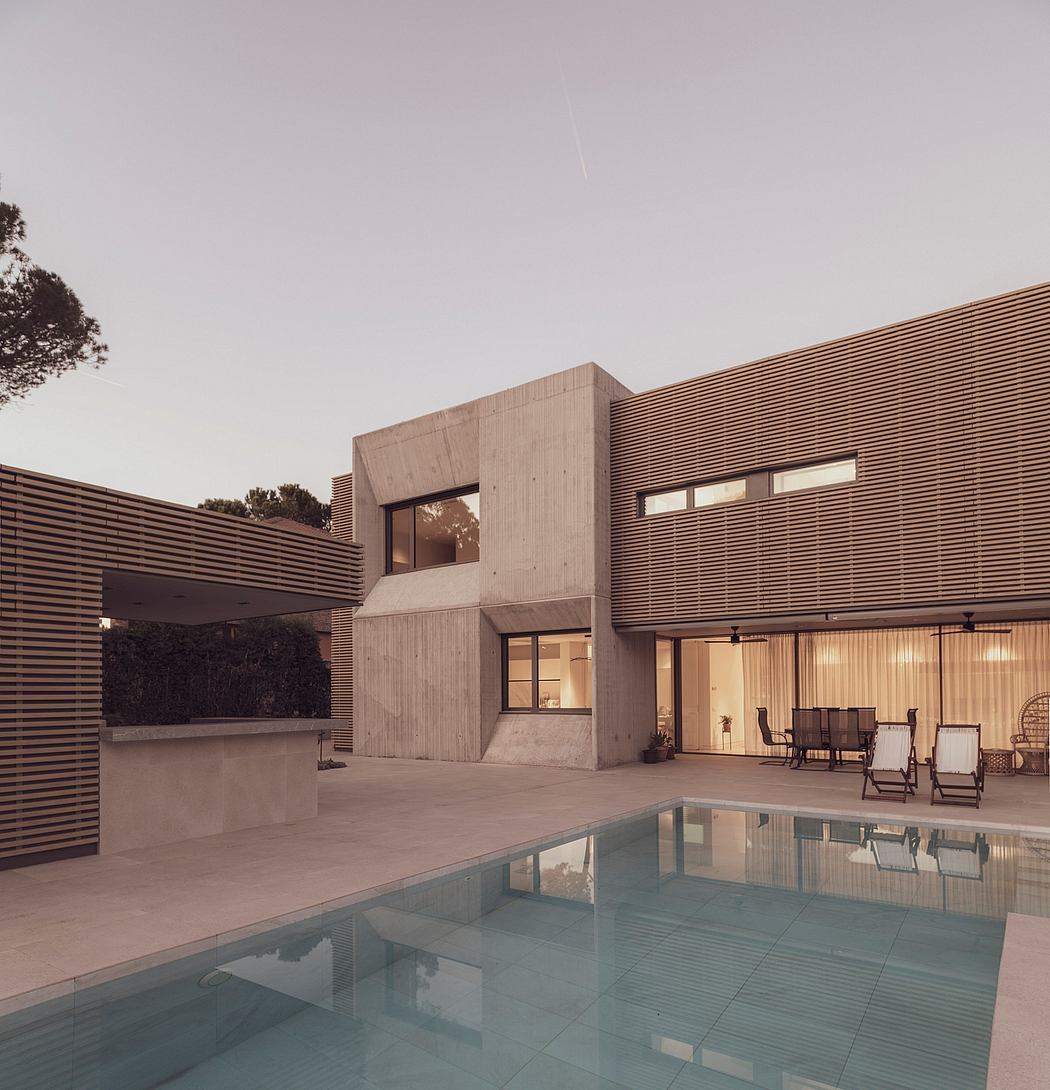 Contemporary house with concrete and wood accents beside a pool at dusk.