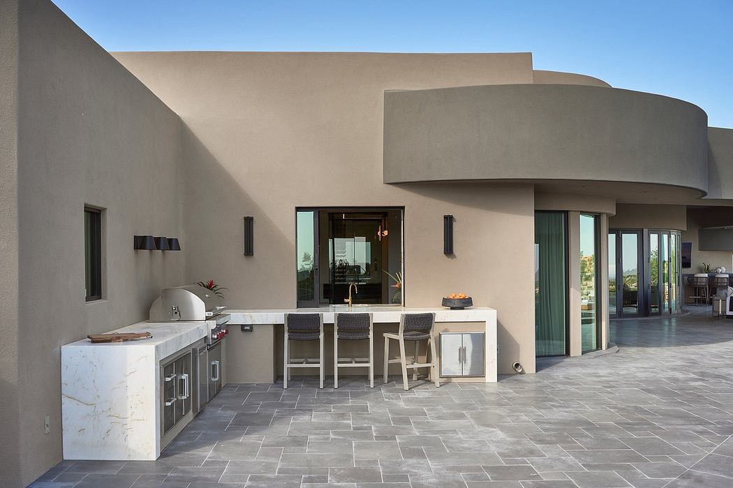Sleek outdoor kitchen area with modern architectural features and stone flooring.