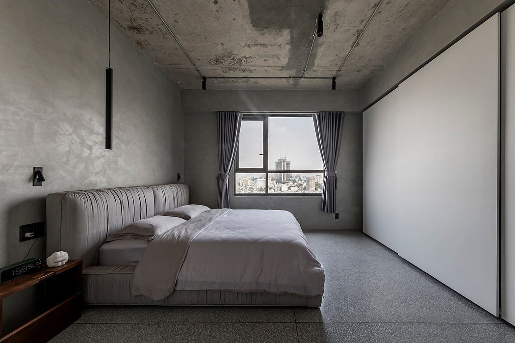 A modern, minimalist bedroom with concrete walls, gray curtains, and a large window overlooking the cityscape.