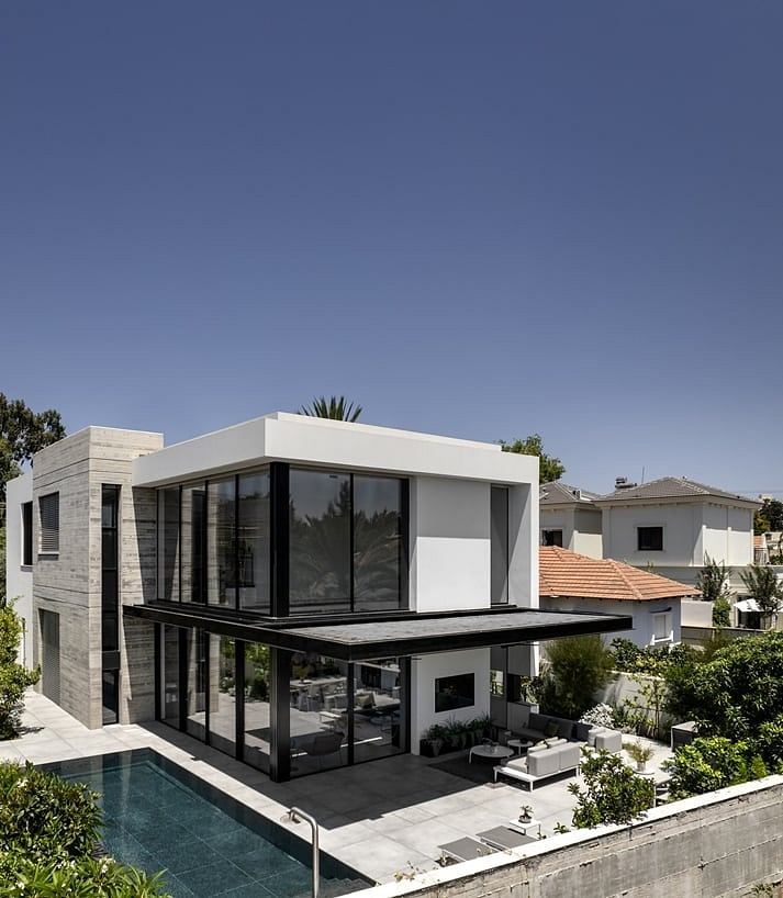 Modern, sleek villa with glass walls, balcony, and swimming pool in lush garden setting.