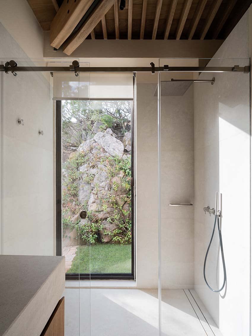 Minimalist bathroom with glass shower and natural view.