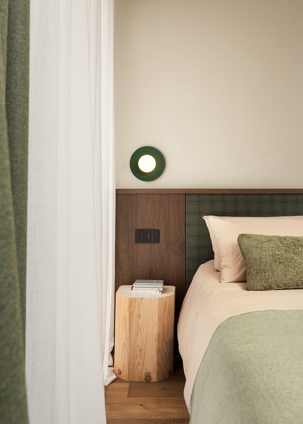 Contemporary bedroom corner with wooden bedside stump and green accents.