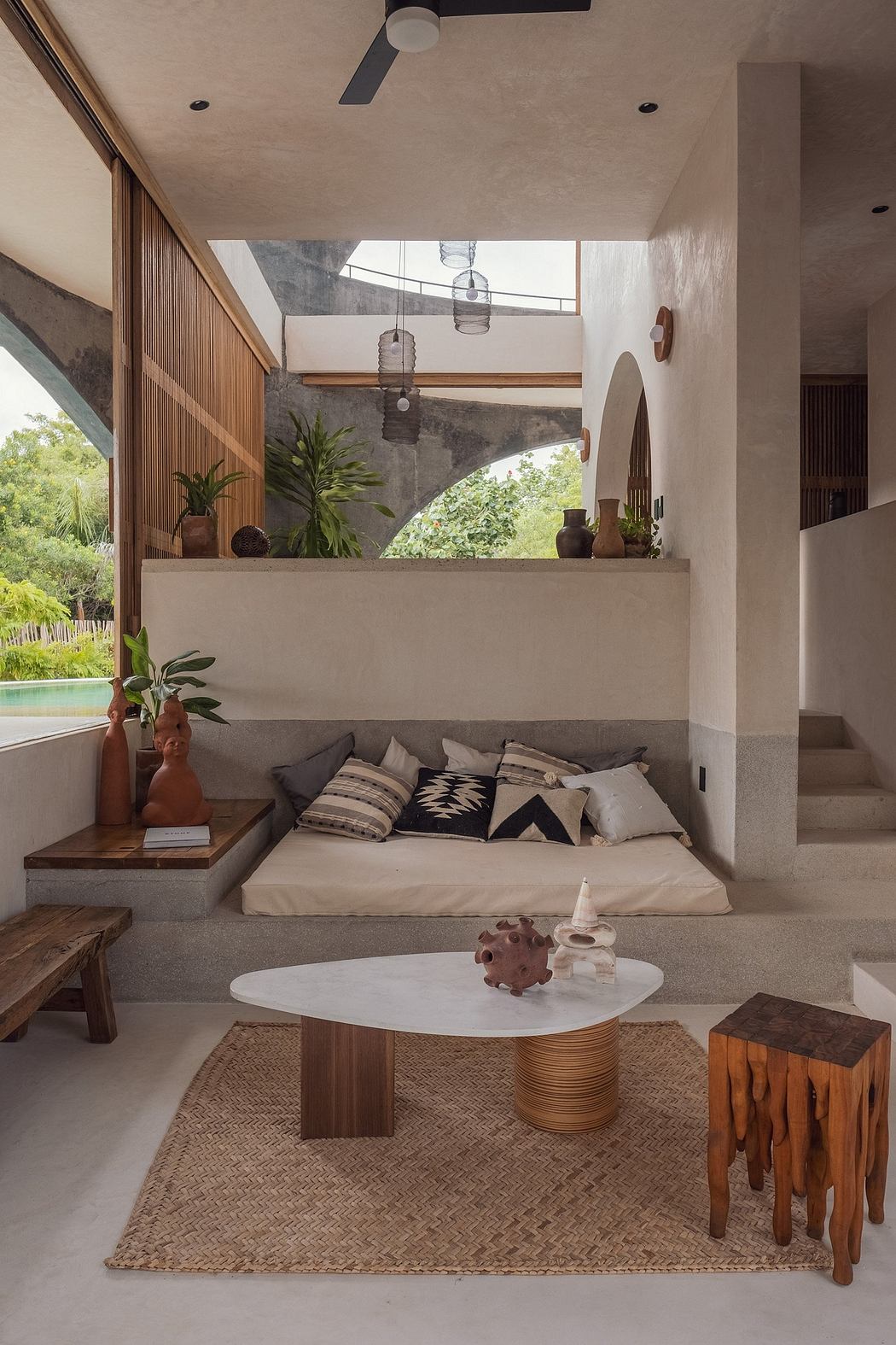 Warm, earthy living space with natural materials, high ceilings, and lush greenery.