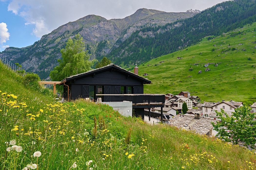 A wooden cabin overlooking a mountain village with alpine scenery.