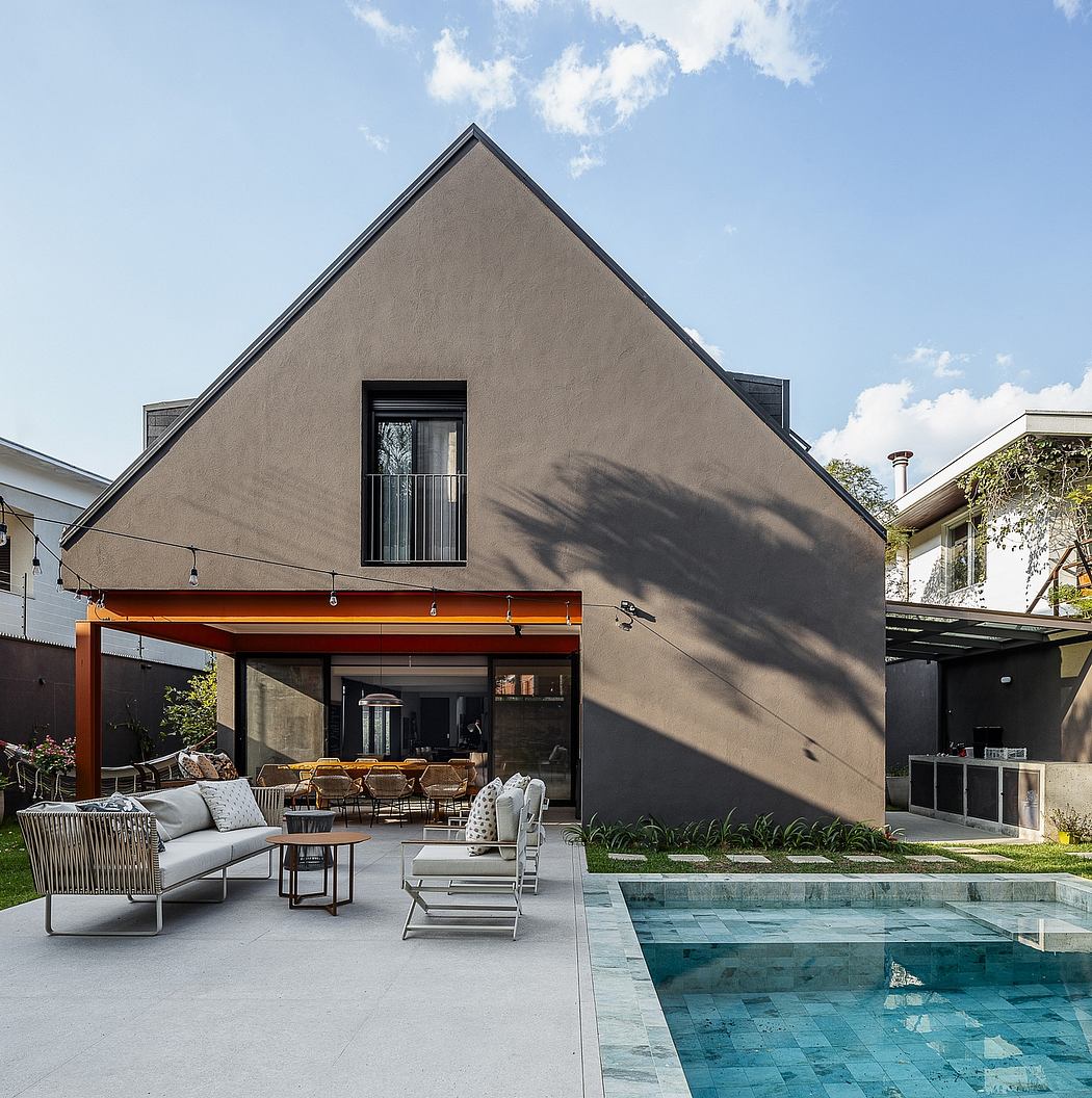 Contemporary A-frame house with poolside outdoor seating.