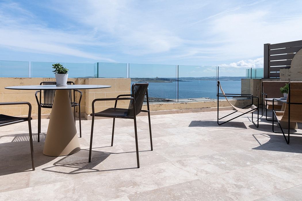 Elegant outdoor seating area with modern furniture, glass walls, and stunning ocean view.