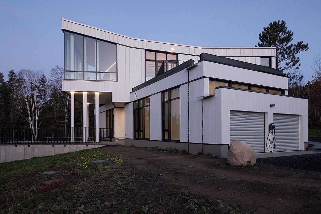 Modern two-story house with large windows and an attached garage at dusk.