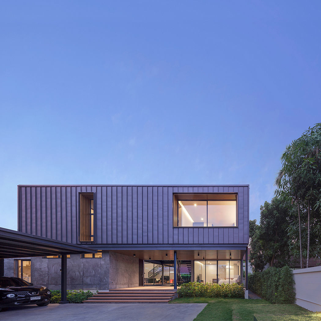 Modern, minimalist two-story home with clean lines, large windows, and a lush landscape.