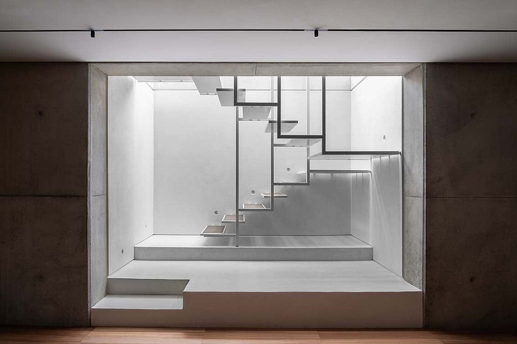 Minimalist stairwell with concrete walls and floating metal steps.
