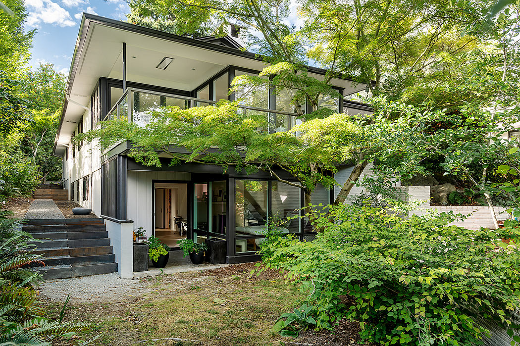 A modern, glass-walled home nestled in lush greenery, with a spacious layout and natural surroundings.