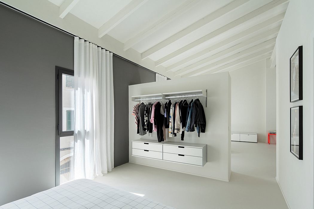 Minimalist walk-in closet with white decor and exposed beams.