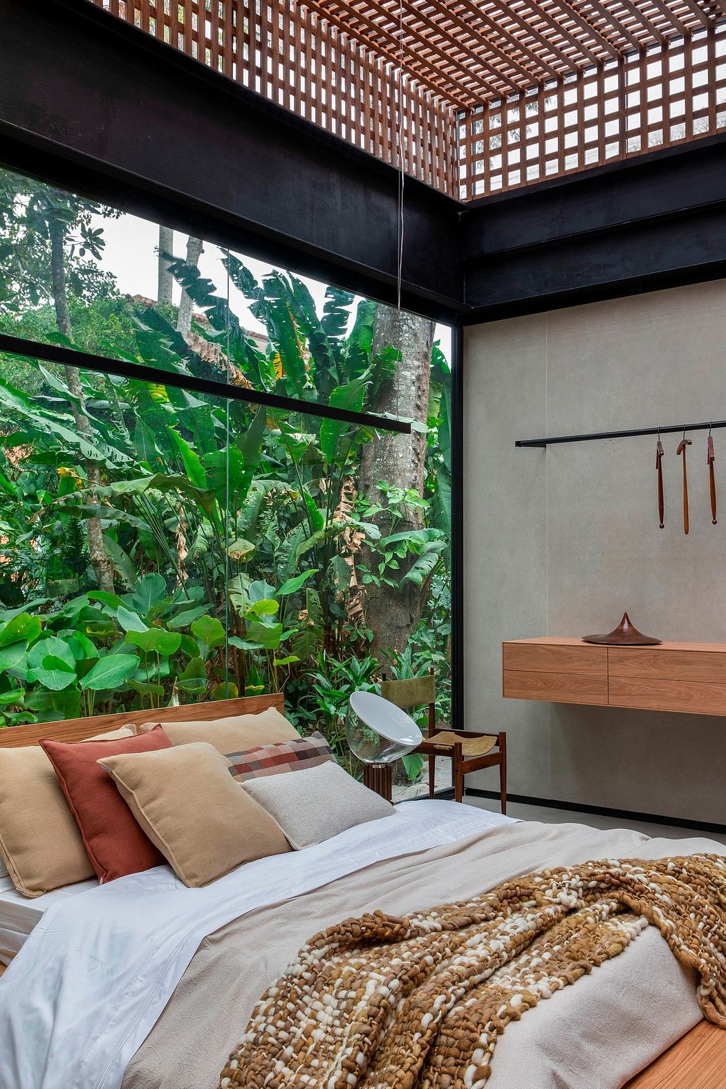 Modern bedroom with large window view of lush greenery.