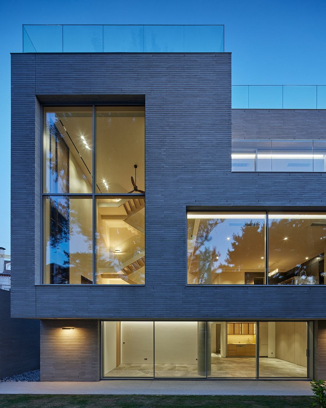 Contemporary house with large glass windows at dusk.