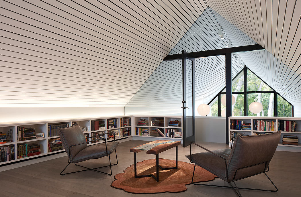 Modern attic library with slanted ceiling, bookshelves, and lounge chairs.