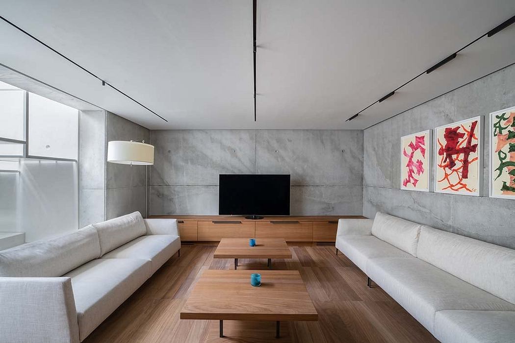 Modern living room with white sofas, wooden table, and grey walls.