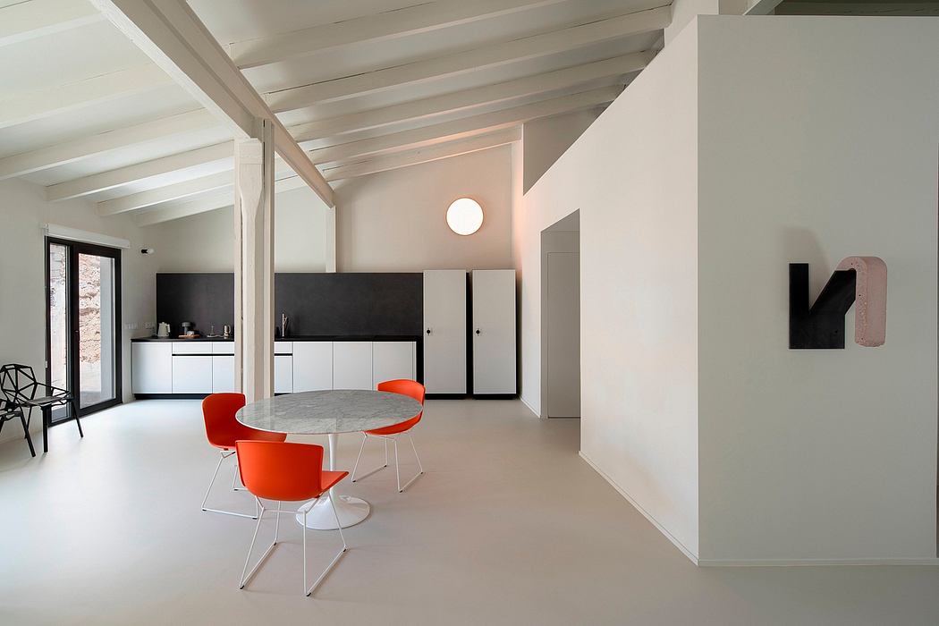 Minimalist interior with white walls, orange chairs, and a round table.