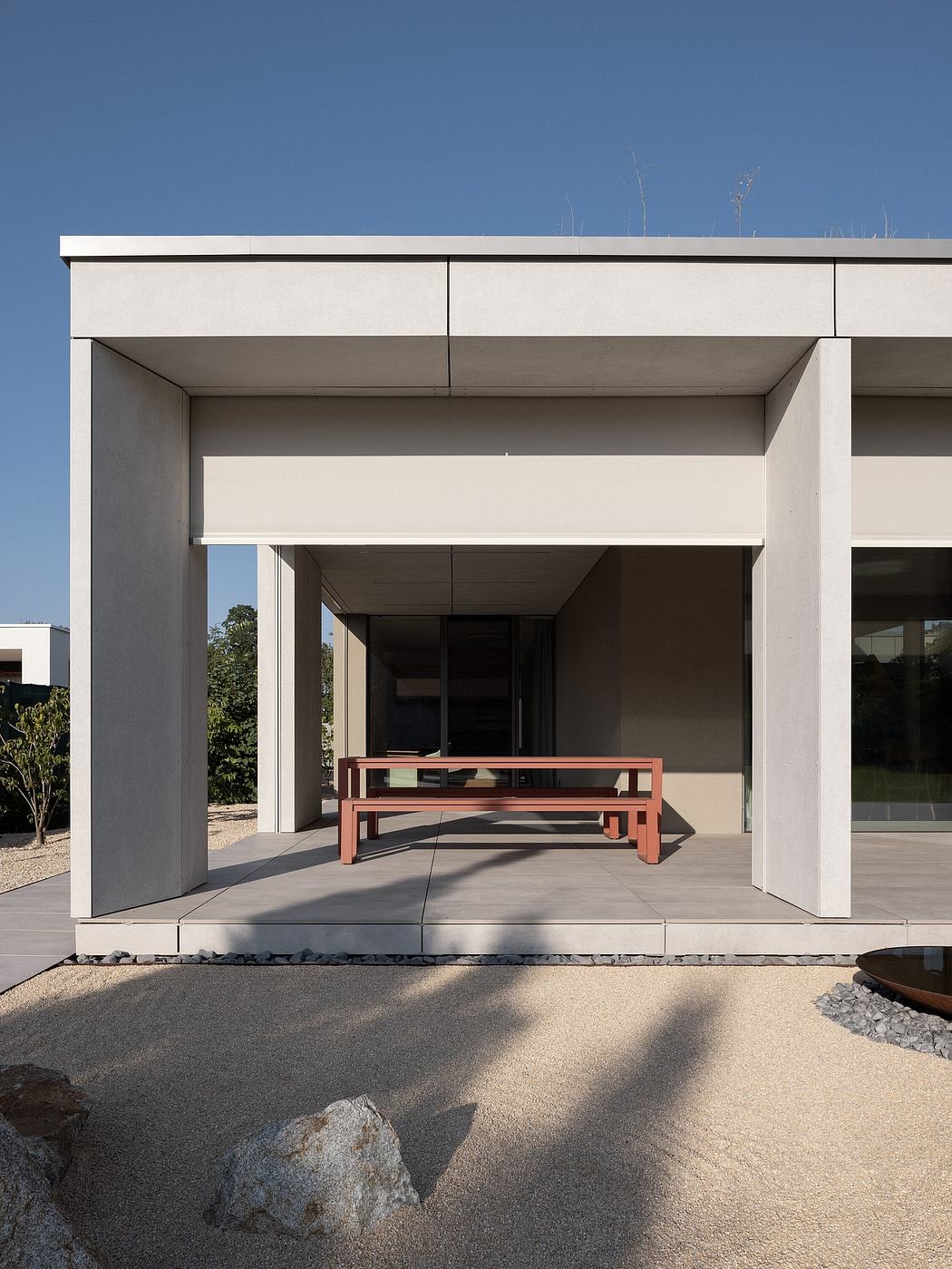 Modern building facade with a bench under a shaded walkway.