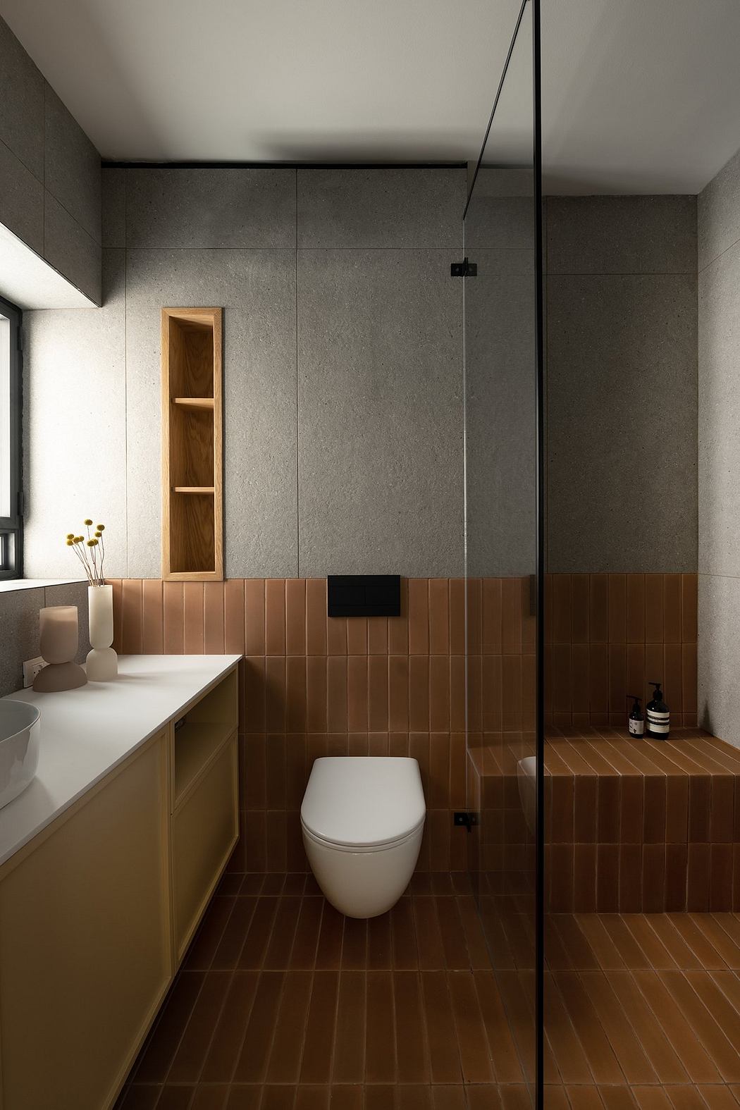 Modern bathroom with glass shower, white toilet, and brown tiles.