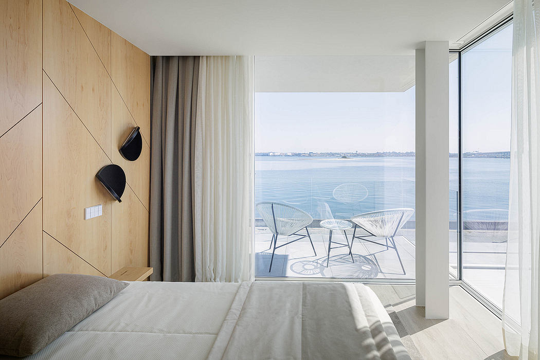 Minimalist bedroom with wooden paneling, floor-to-ceiling windows, and modern outdoor furniture.