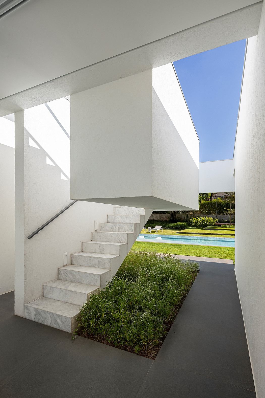 Modern architectural design featuring a sleek staircase, skylights, and lush landscaping surrounding a pool.