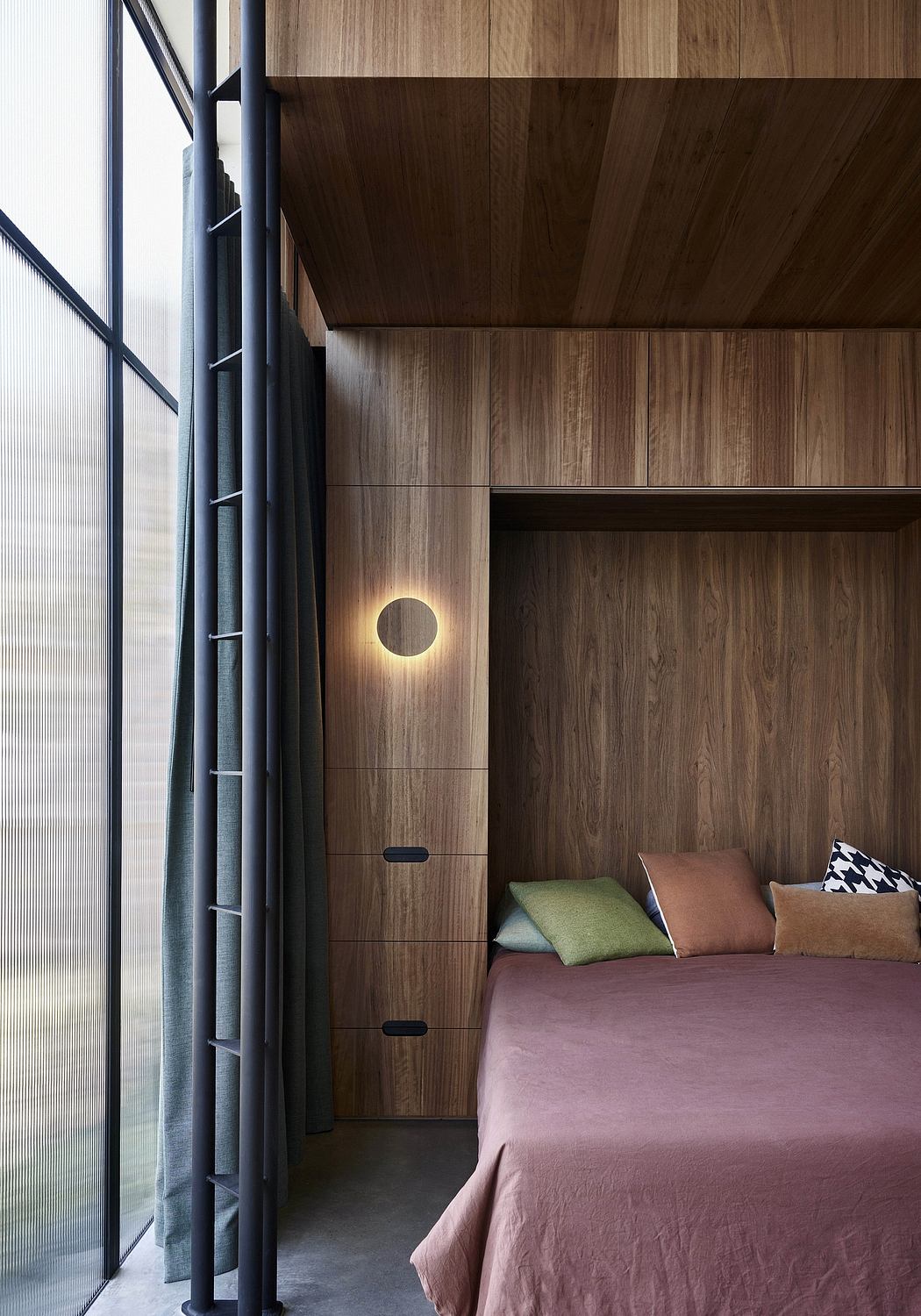 A cozy bedroom with warm wooden walls, minimalist shelving, and a circular wall light.