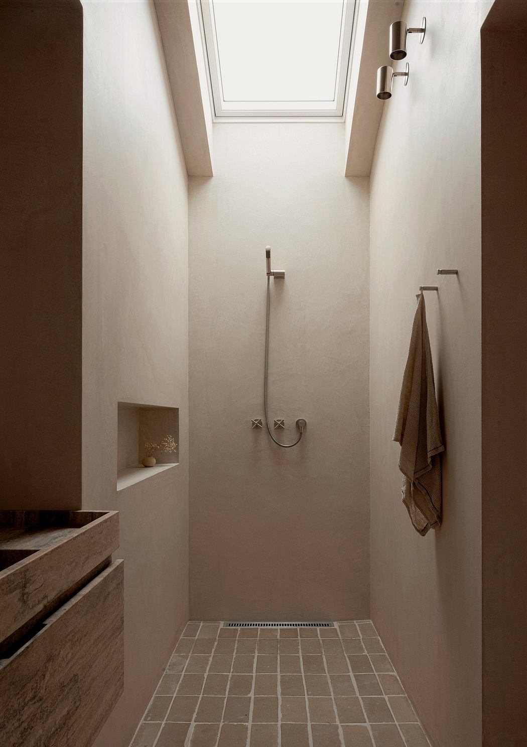 Narrow minimalist shower with skylight and neutral tones.