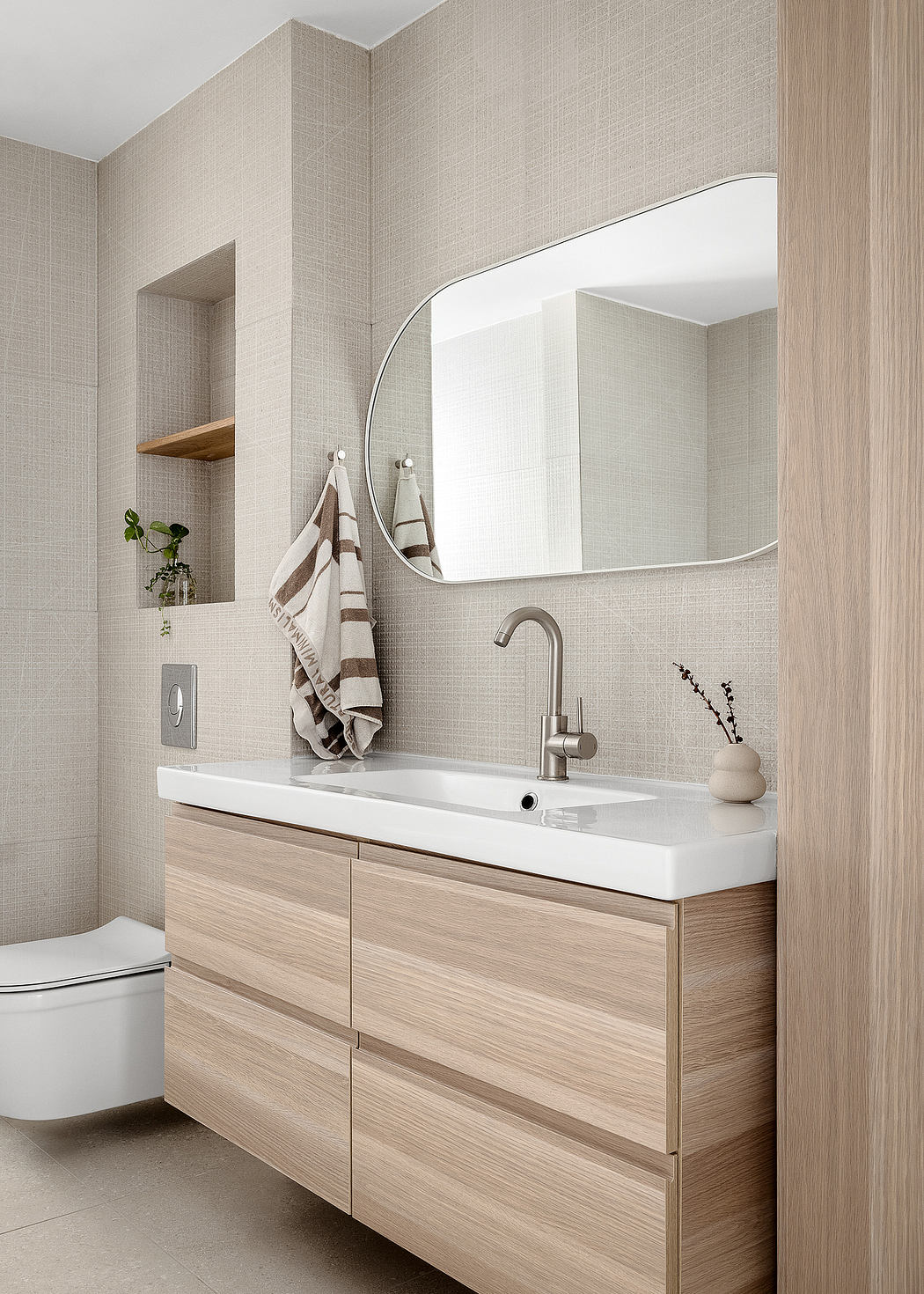 Modern bathroom with wooden vanity, mirror, and white fixtures.