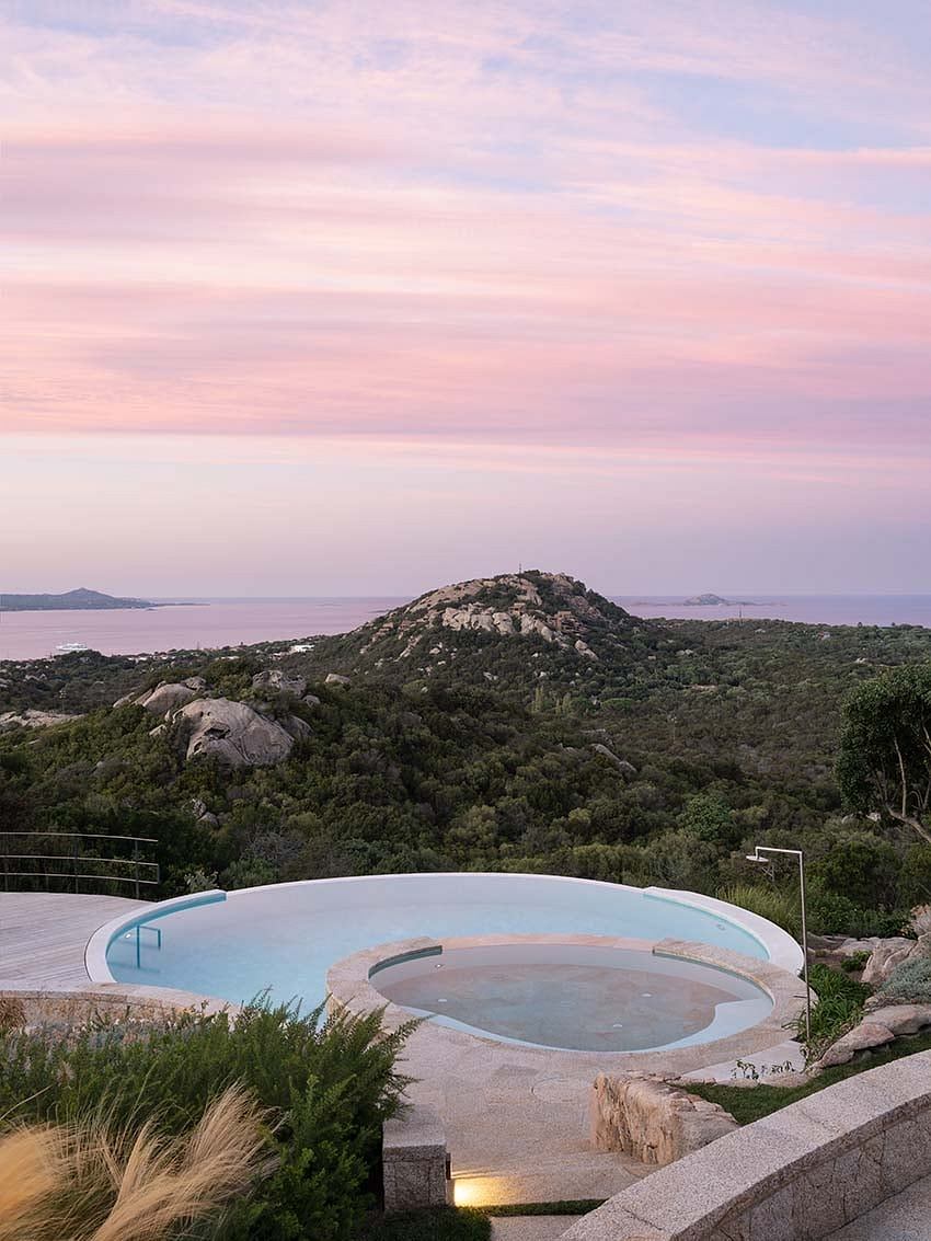 Infinity pool overlooking a scenic hillside at dusk.