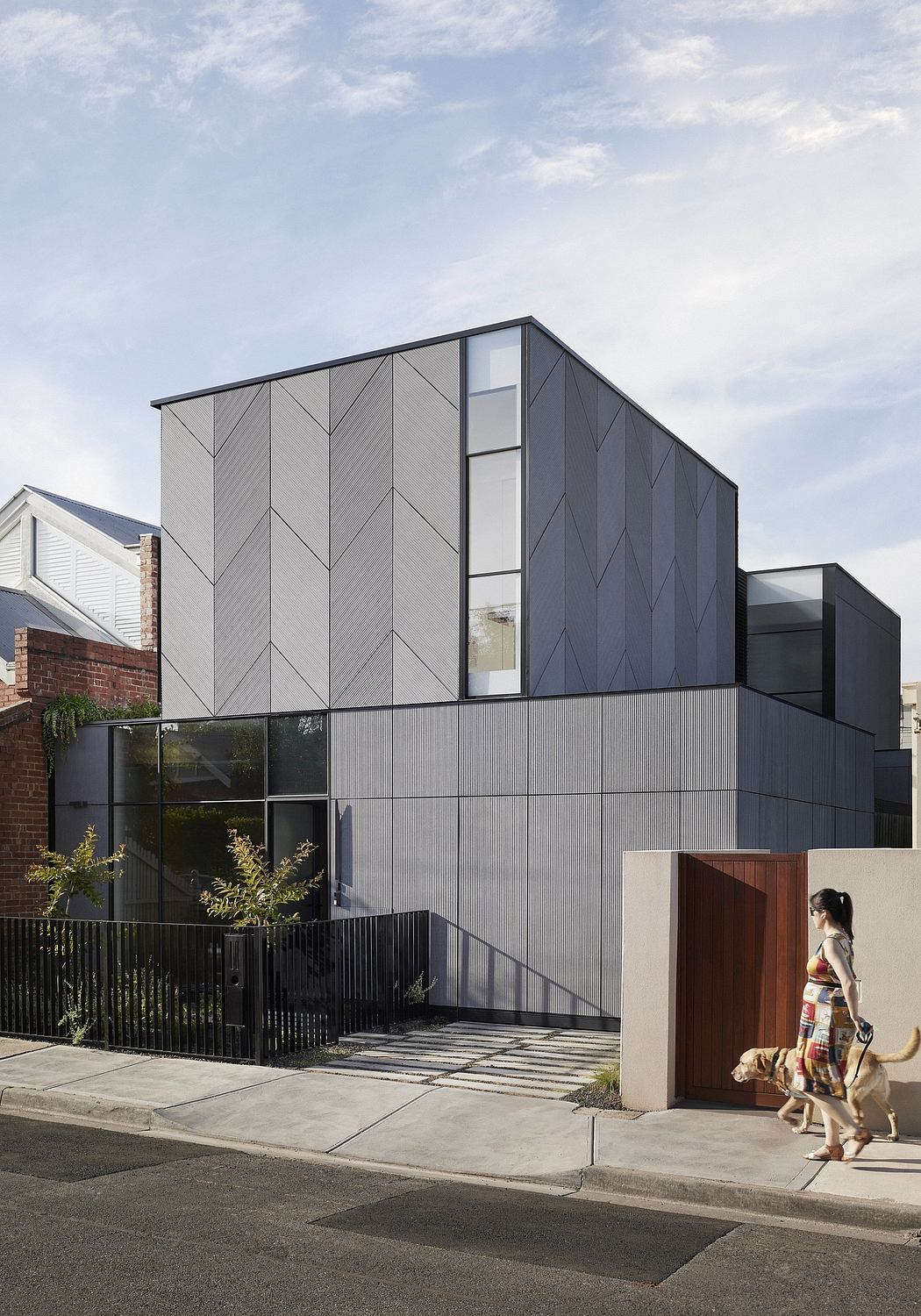 A modern, geometric exterior with striking black panels and large windows. The entryway features a wood-paneled door.