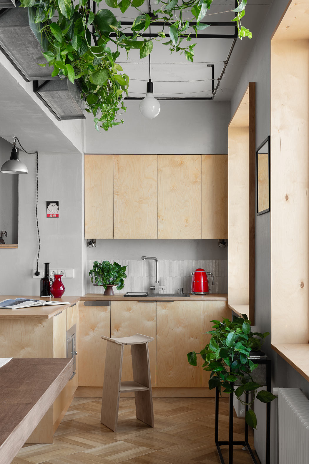 Cozy kitchen with rustic wood cabinets, hanging plants, and modern industrial lighting.
