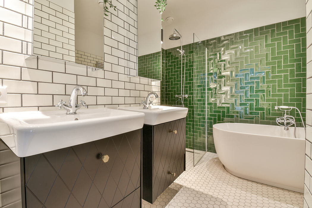 Contemporary bathroom with green tiled shower and freestanding tub.