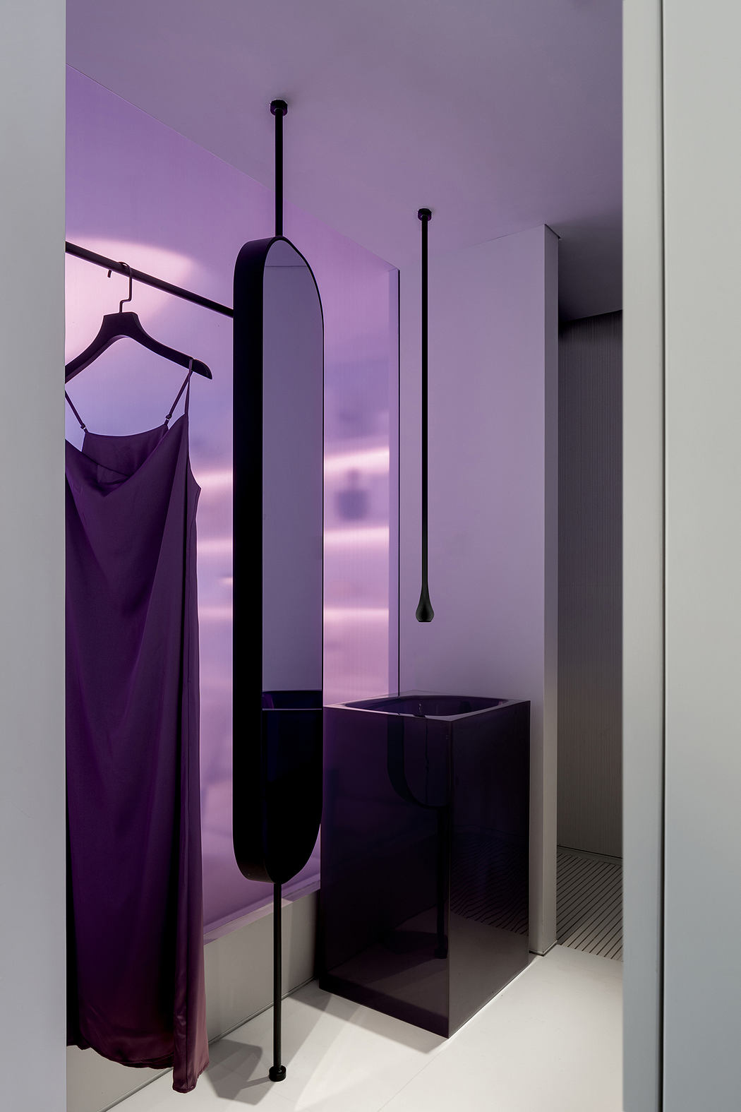 Sleek, modern bathroom with striking purple walls, minimalist fixtures, and a hanging rack.