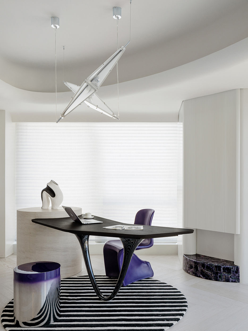 Minimalist office space with geometric furniture, bold lighting, and striking black-and-white rug.