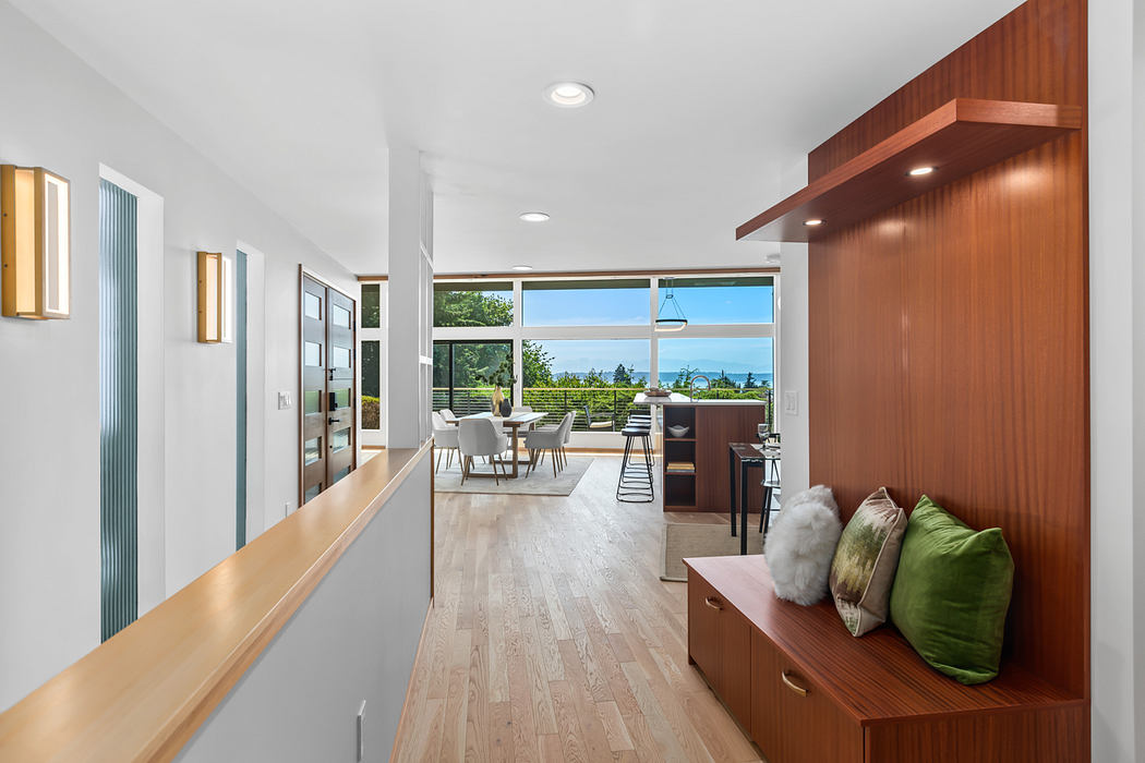 A modern, open-plan living space with wood paneling, large windows, and an outdoor view.