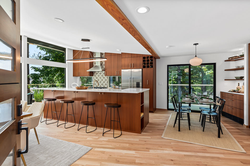 Sleek mid-century style kitchen with wood cabinetry, island seating, and large windows.