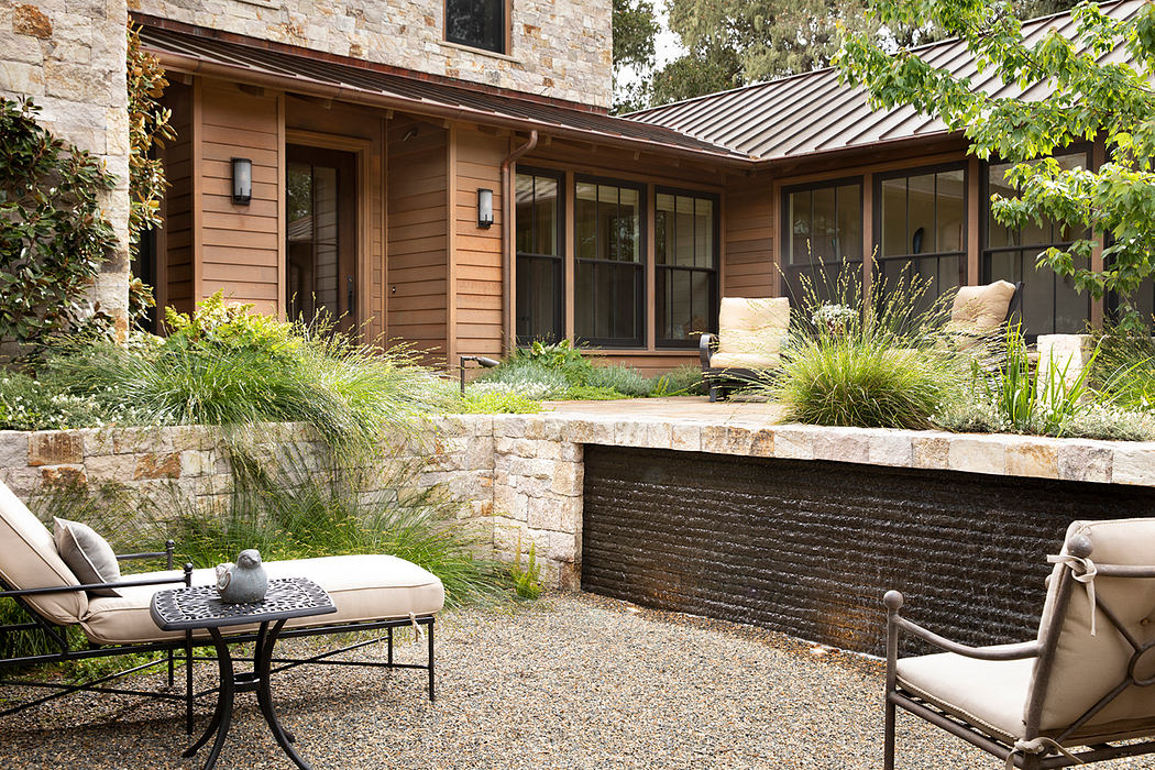 A cozy, modern home with a stone exterior, covered patio, and peaceful water feature.
