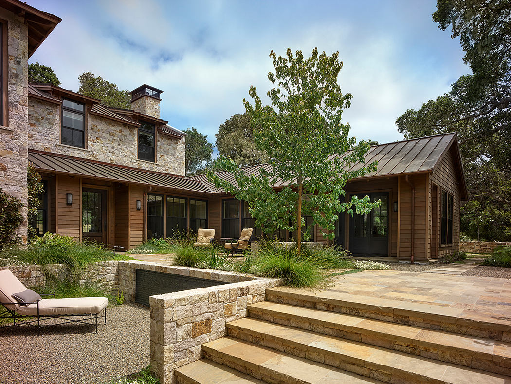 An elegant stone and wood home with a well-designed outdoor living space and landscaping.