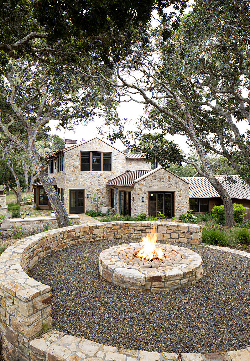 Rustic stone house surrounded by lush foliage, featuring a cozy outdoor firepit.