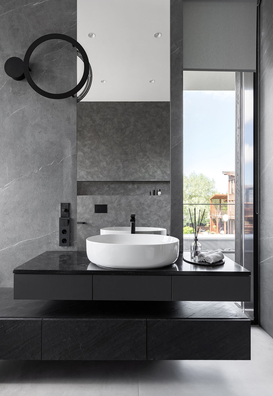 Sleek, modern bathroom with black vanity, round white basin, and large mirror.