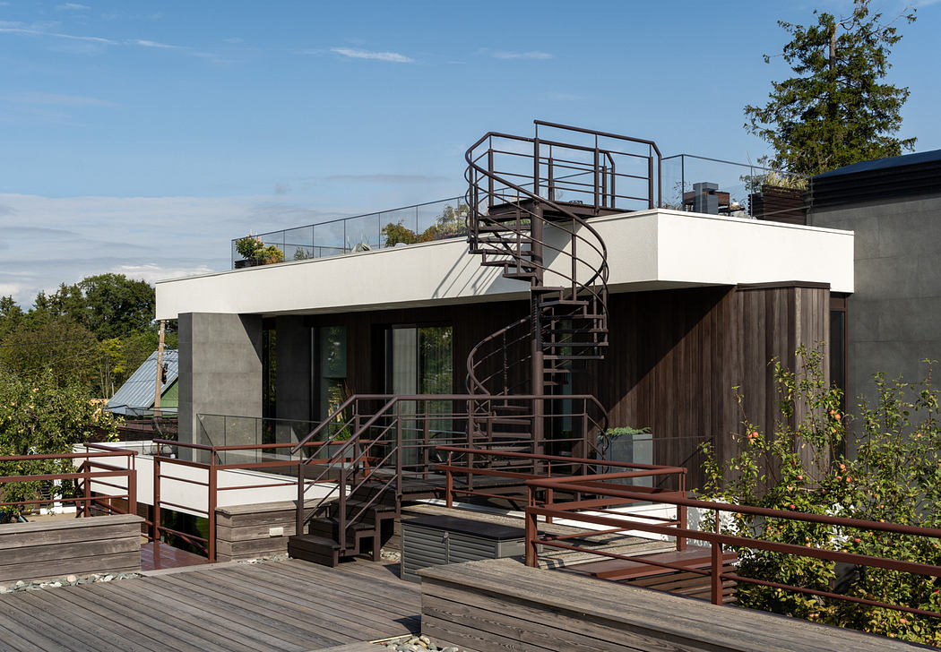 A modern, multi-level house with a spiral staircase, wooden decks, and large glass windows.