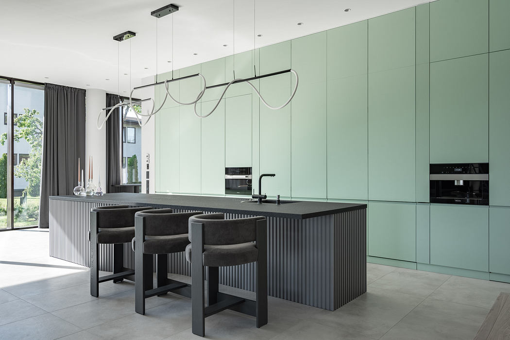 A modern kitchen with sleek green cabinetry, black island, and sculptural pendant lights.