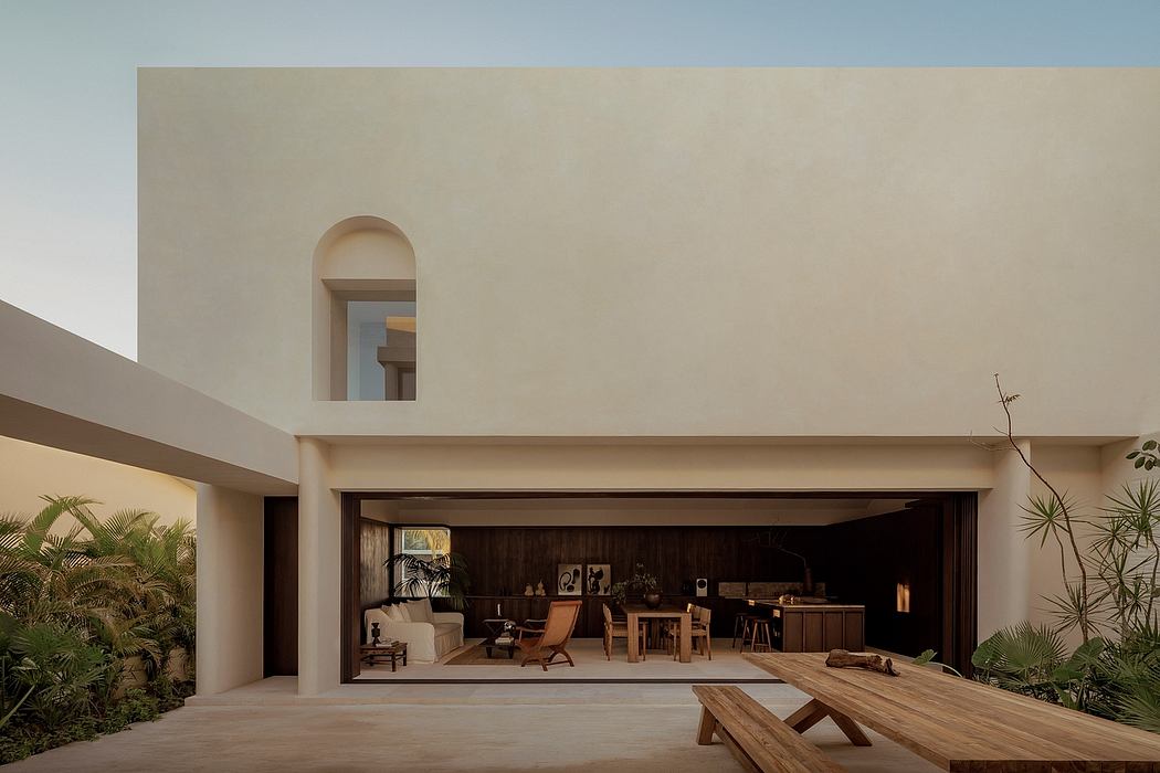 Minimalist contemporary architecture with arched entryway, wooden furnishings, and lush greenery.