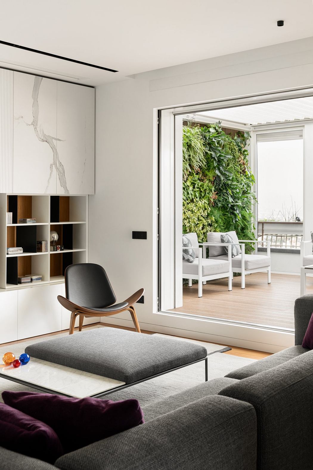 Sleek modern living room with floor-to-ceiling window, built-in shelving, and lush greenery.