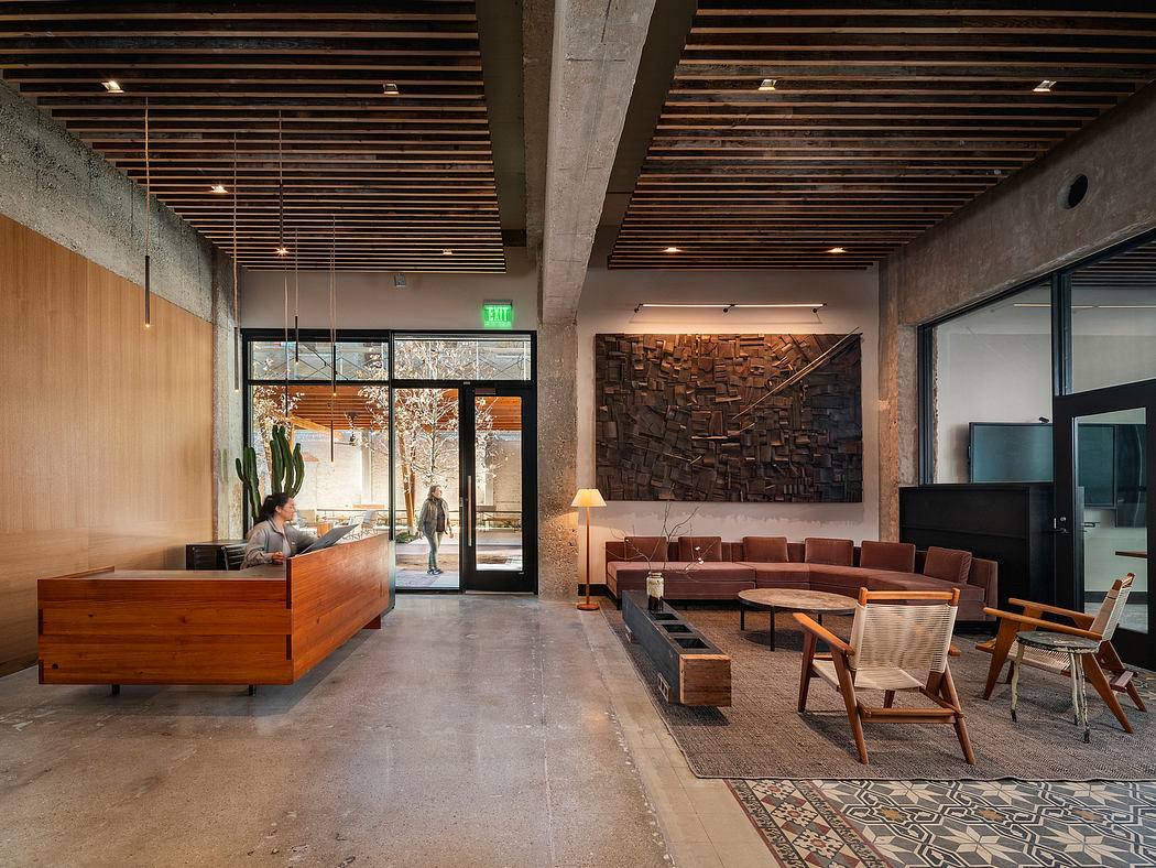 A spacious, modern lounge with exposed concrete walls, wood beams, and a large abstract artwork.
